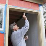 Jiff Searing paints the door frame of the tiny house during the volunteer event on Saturday. Evan Pappas/Staff Photo