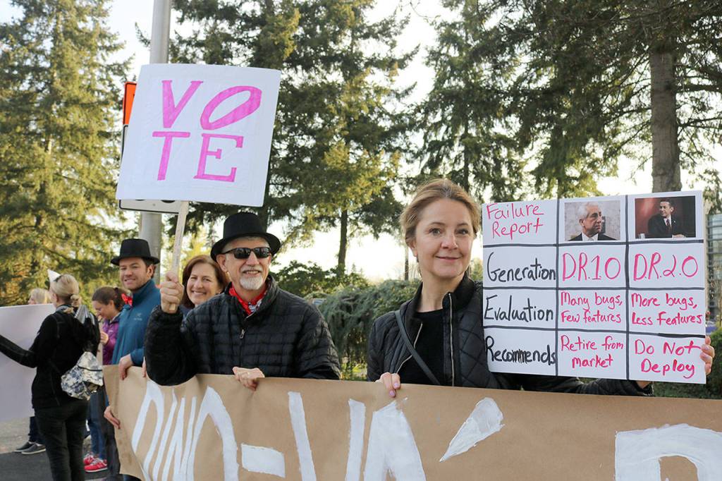 Chris Petzold, organizer at Indivisibles of Washington’s 8th District, holds up a sign along with other attendees of the rally. Evan Pappas/Staff Photo