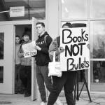 Bellevue High School student Charlie Kern holds a sign calling for more guns, less crime as another student holds a sign that reads books, not bullets. The walkout was student-led and students were able share their opinions and have a dialogue with one another. Raechel Dawson/staff photo