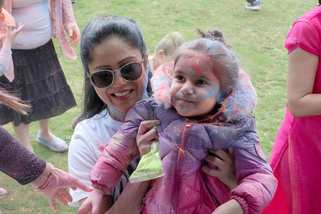 Priyanka Pathak lifts her daughter Dia to the stage to get some Holi color. Evan Pappas/Staff Photo