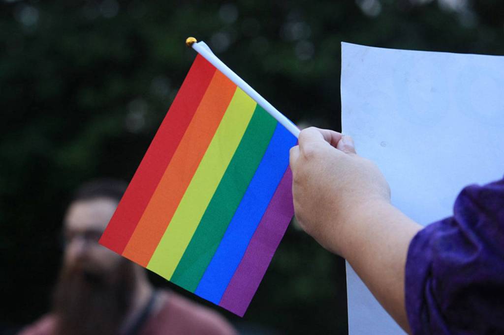A supporter of the Drag Queen Story Hour event holds a sign and Pride flag standing across the parking lot of the Fairwood Library from a protester on June 27. Aaron Kunkler/staff photo