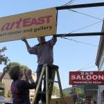 Mike Bossing removes the ArtEast sign during its closing party. From left: David Lutrick, Monica Phillips and Mike Bossing.