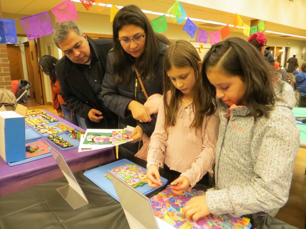 Samantha Pak/staff photo                                From left, Luis Nunez, Catalina Nunez, Angie Nunez and Leslie Gonzalez pick out items at the Dia De Los Muertos celebration in downtown Issaquah. The items are for a miniature altar they will create as a family.