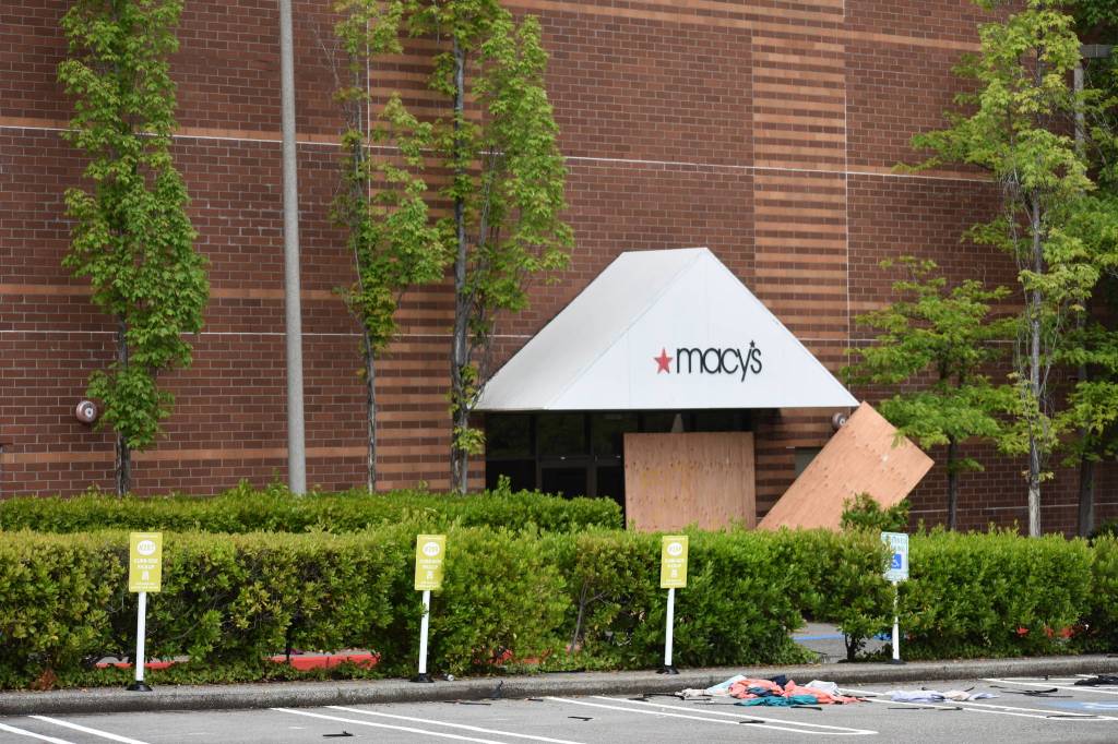 While protesters and police were a few yards away, people moved in and out of the Bellevue Square Mall with arms full of clothes shoes and other merchandise on Sunday, May 31. Photo by Haley Ausbun/Sound Publishing