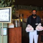 Kabal Gill, owner of East India Grill in Federal Way, wears gloves to hand over take-out orders at his restaurant. File photo