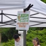 Stands with the Supplemental Nutrition Assistance Program (SNAP) Market Match sign allows people to increase the purchasing power of SNAP when purchasing fruits and vegetables at the Issaquah Farmers Market. The program will provide $1 for every SNAP $1 spent on fruit and vegetables  up to $25 per day per customer. SNAP-eligible items include fresh fruits, vegetables, mushrooms, fresh herbs and edible plant starts. (Cameron Sires/ Sound Publishing)